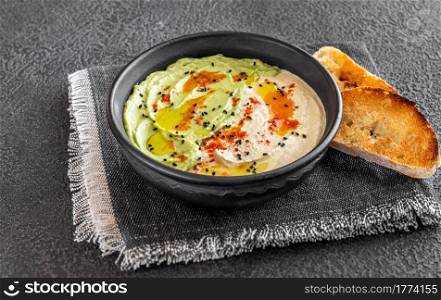 Bowl of guacamole and hummus with toasted bread
