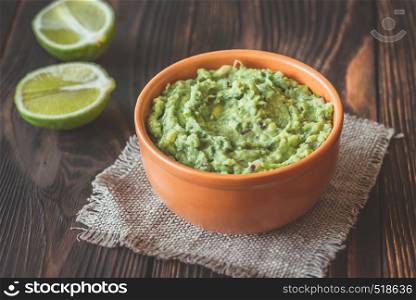 Bowl of guacamole on the wooden table close-up