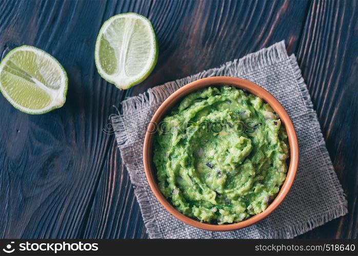 Bowl of guacamole on the wooden table close-up