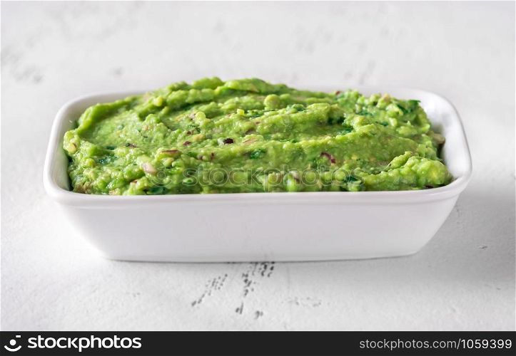 Bowl of guacamole on white background