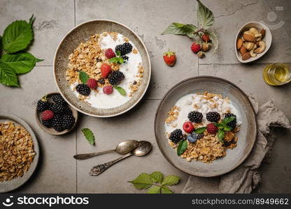 Bowl of homemade granola with yogurt and fresh berries on gray background from top view. Bowl of homemade granola