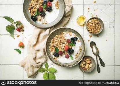 Bowl of homemade granola with yogurt and fresh berries on white background from top view. Bowl of homemade granola