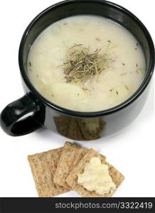 Bowl of homemade herb potato soup and wheat crackers with butter.