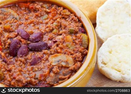 Bowl of hot Chili Con Carne with a side of hot buttered biscuits.