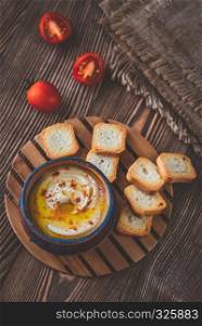 Bowl of hummus with cherry tomatoes and toasts