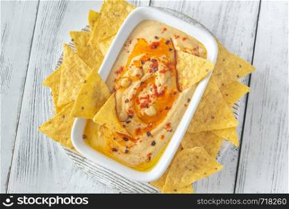 Bowl of hummus with tortilla chips on the wooden table