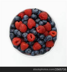 Bowl of mixed blueberries and raspberries on white background.