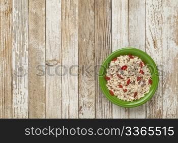bowl of muesli cereal with raisins, flux seeds and goji berries against grunge wood table