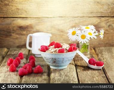 bowl of muesli with raspberry on wooden background