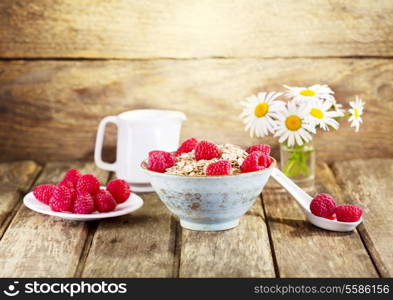 bowl of muesli with raspberry on wooden background