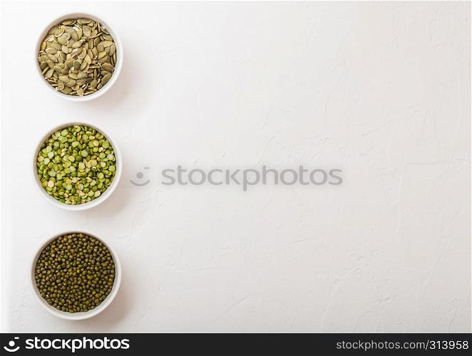 Bowl of mung beans and split peas and pumkin seeds on white kitchen background
