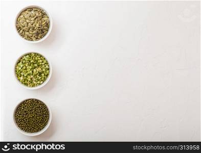 Bowl of mung beans and split peas and pumkin seeds on white kitchen background