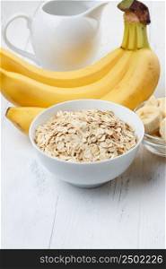 Bowl of oat flakes with sliced banana close-up on wooden table