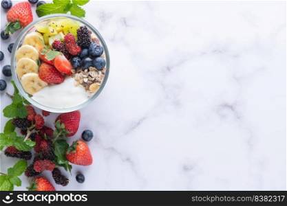 bowl of oat granola with yogurt, fresh blueberries, mulberry, strawberries, kiwi, banana, mint and nuts board for healthy breakfast, top view, copy space, flat lay. vegetarian food concept.