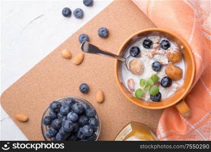 bowl of oatmeal porridge with blueberries, fruits, almonds and coconut milk. Healthy and tasty vegan breakfast. top view, flat lay.