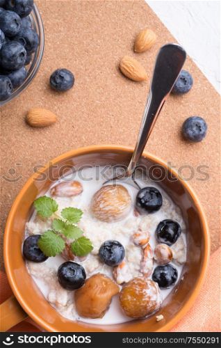 bowl of oatmeal porridge with blueberries, fruits, almonds and coconut milk. Healthy and tasty vegan breakfast. top view, flat lay.close up