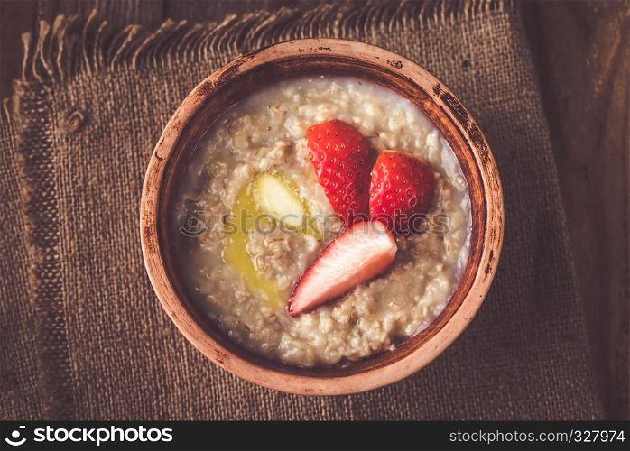 Bowl of oats with fresh strawberries on the wooden table