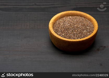 Bowl of organic natural chia seeds close-up on wooden background or table. High quality photo. Bowl of organic natural chia seeds close-up on wooden background or table