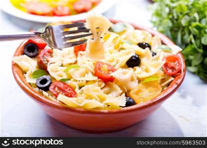 bowl of pasta salad with vegetables on wooden table