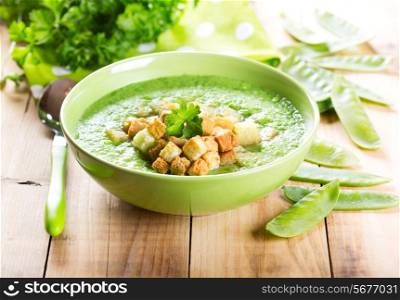 bowl of pea soup with croutons on wooden table
