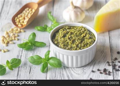 Bowl of pesto with ingredients on the white wooden background