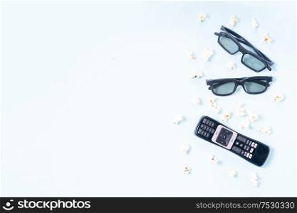 bowl of popcorn, nd remote control for TV and 3d glasses over blue background with copy space, movie and cinema concept. popcorn and 3d glasses