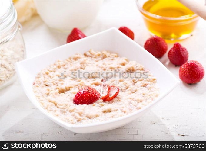 bowl of porridge with strawberry on wooden table