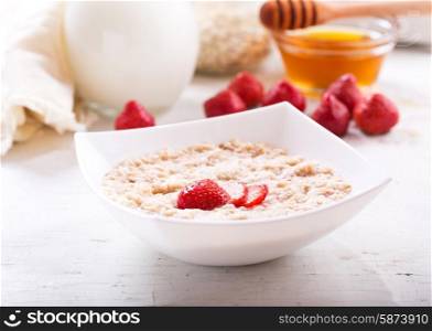 bowl of porridge with strawberry on wooden table