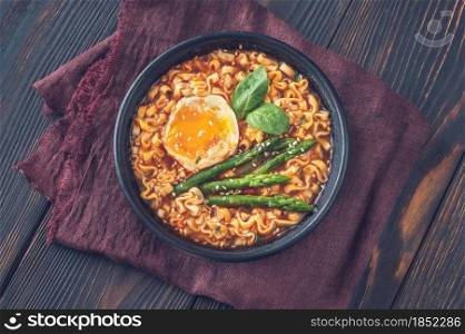 Bowl of ramen with soft-boiled egg and asparagus on the wooden table