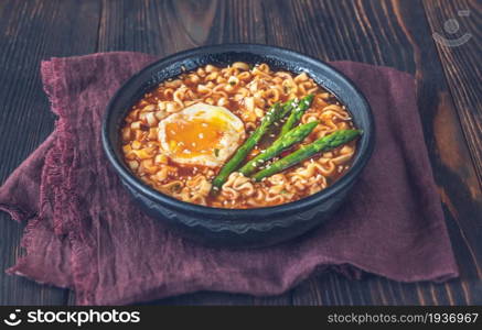 Bowl of ramen with soft-boiled egg and asparagus on the wooden table