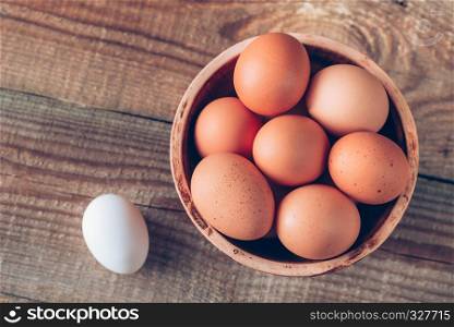 Bowl of raw chicken eggs on the wooden background