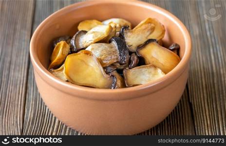 Bowl of raw king oyster mushrooms on wooden  background