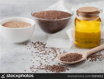 Bowl of raw natural organic linseed flax-seed with spoon and glass jar oil on light background with linen cloth.