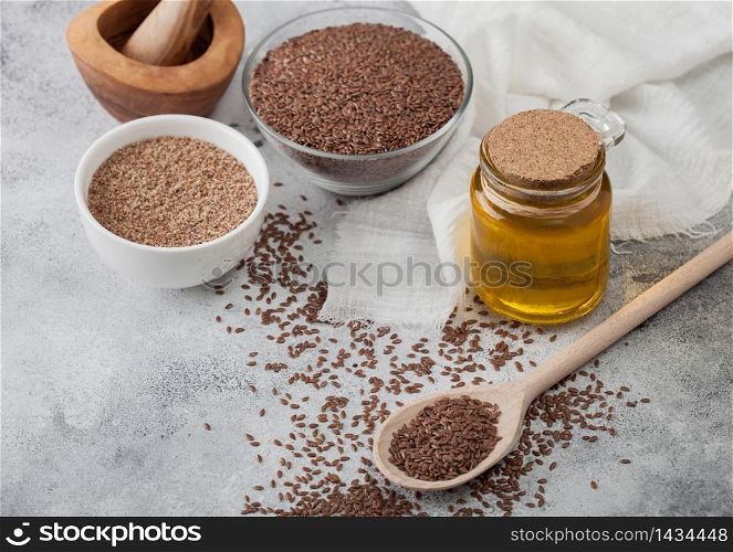 Bowl of raw natural organic linseed flax-seed with spoon and glass jar oil on light background with linen cloth. Mixed seeds powder in white bowl.