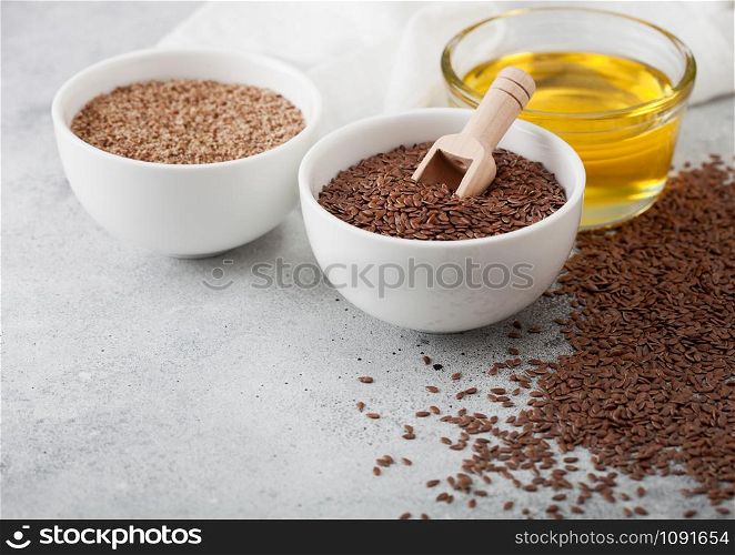 Bowl of raw natural organic linseed flax-seed with spoon and oil on light background with linen cloth. Top view