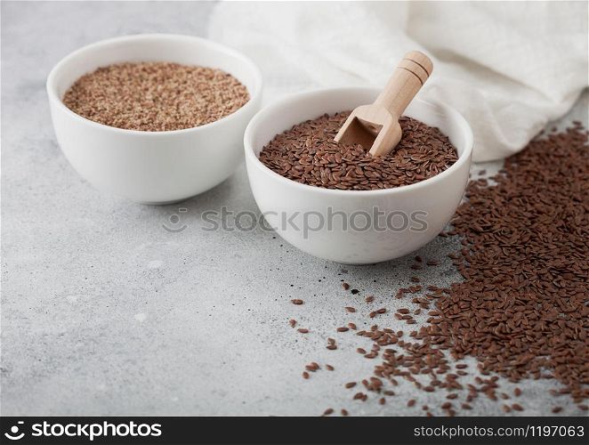 Bowl of raw natural organic linseed flax-seed with spoon and powder on light background with linen cloth.