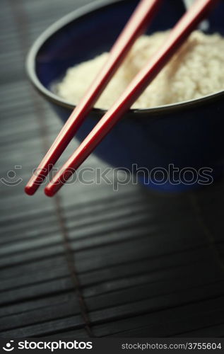 Bowl of rice and chopsticks over black