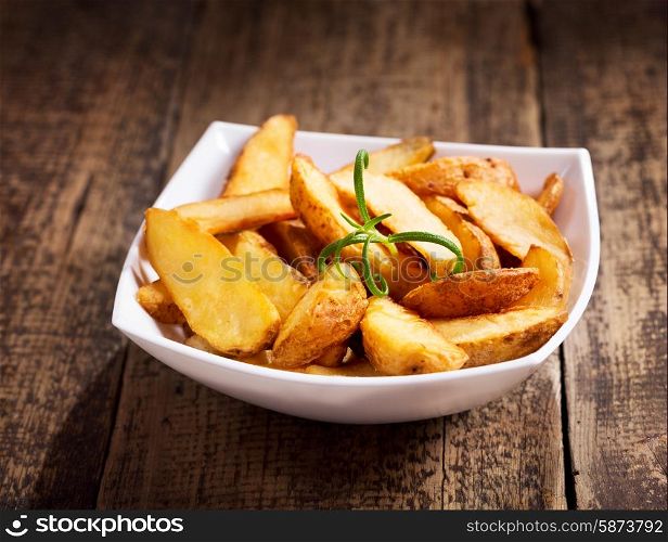 bowl of roasted potatoes with rosemary on wooden table