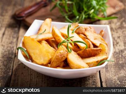 bowl of roasted potatoes with rosemary on wooden table