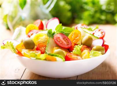 bowl of salad with fresh vegetables on wooden table