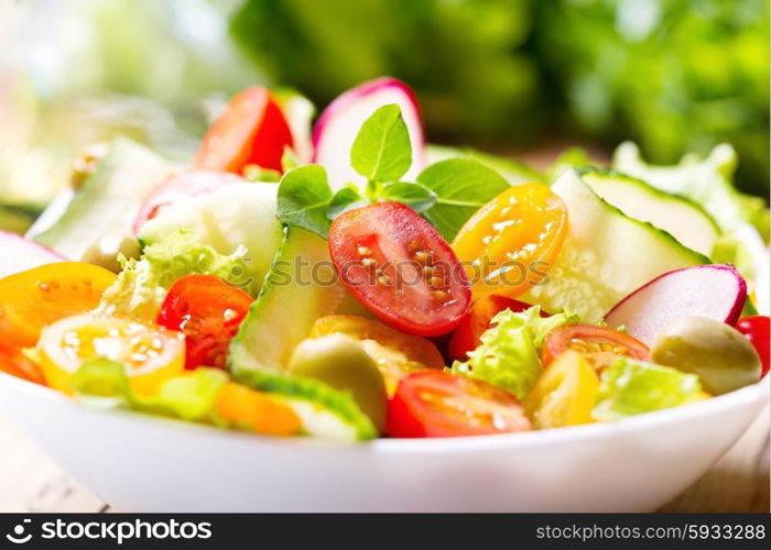 bowl of salad with fresh vegetables on wooden table