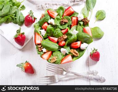 bowl of salad with strawberry, spinach leaves and feta cheese, top view