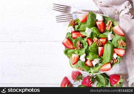 bowl of salad with strawberry, spinach leaves and feta cheese, top view