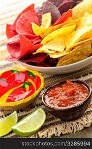 Bowl of salsa with colorful tortilla chips and lime