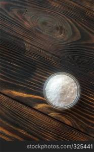 Bowl of salt on the wooden background