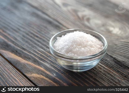 Bowl of salt on the wooden background