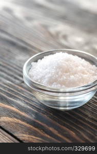 Bowl of salt on the wooden background