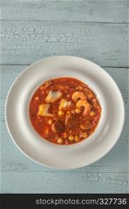 Bowl of spanish fish and chorizo soup on the wooden table