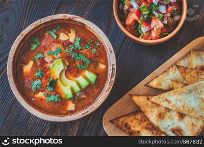 Bowl of spicy Mexican soup with grilled tortillas and salsa
