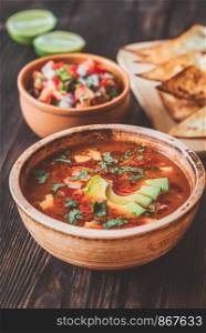 Bowl of spicy Mexican soup with grilled tortillas and salsa
